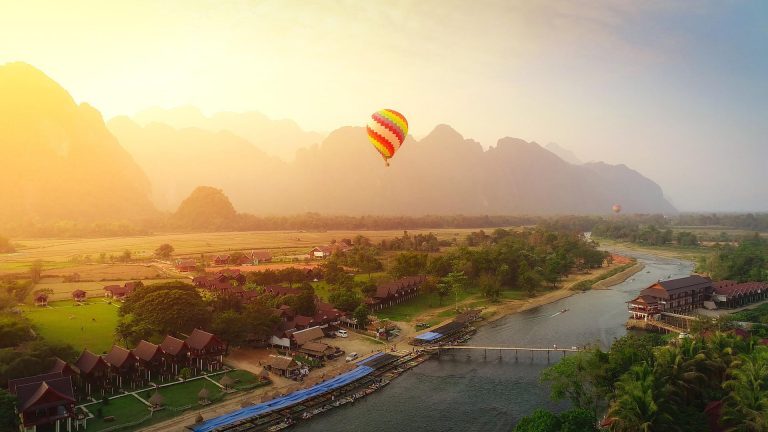 ทิวทัศน์หุบเขาและแม่น้ำยามพระอาทิตย์ขึ้น มีบอลลูนลอยอยู่เหนือหมู่บ้าน