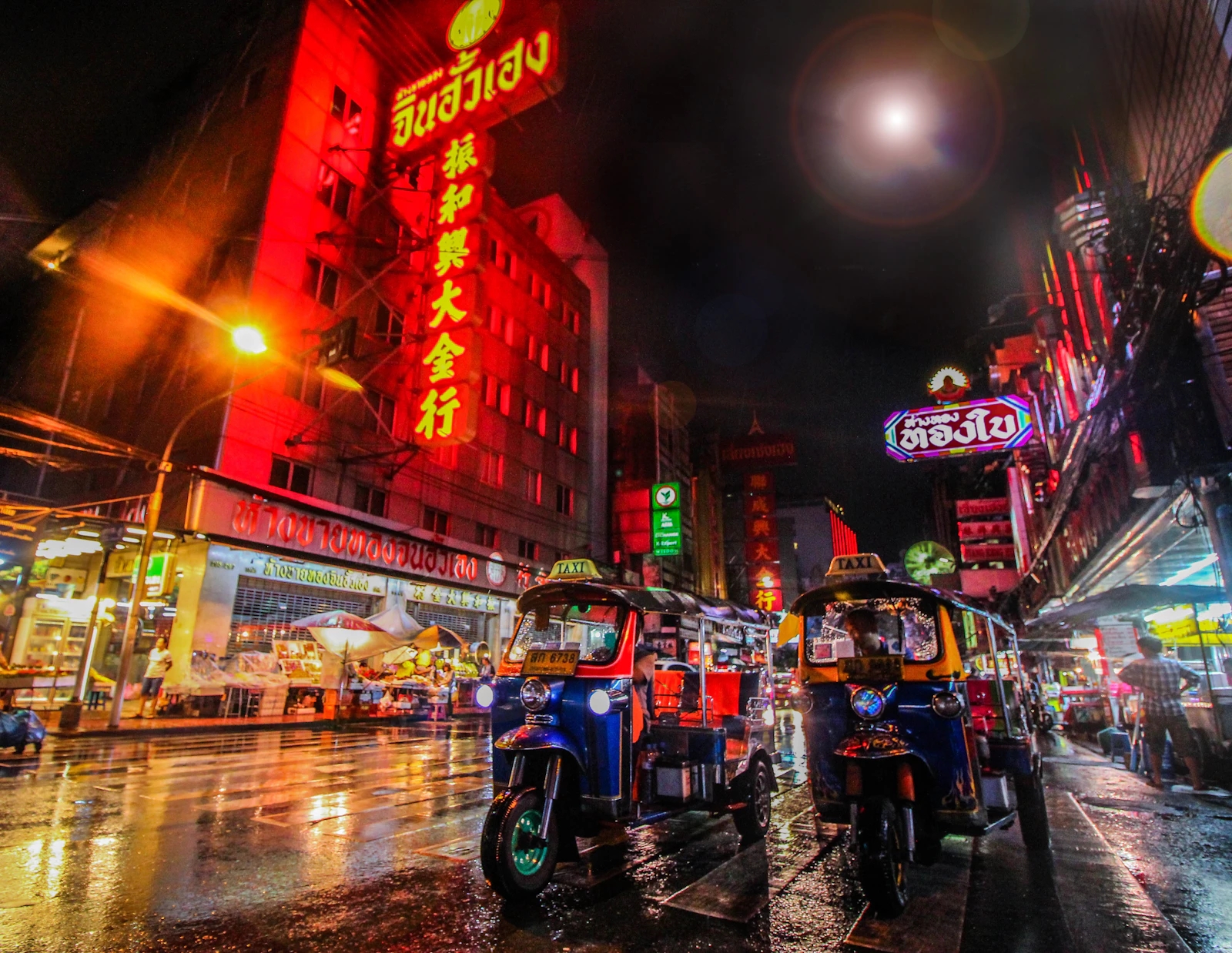 ถนนย่านเยาวราชยามค่ำคืน แสงไฟป้ายร้านและรถตุ๊กตุ๊ก